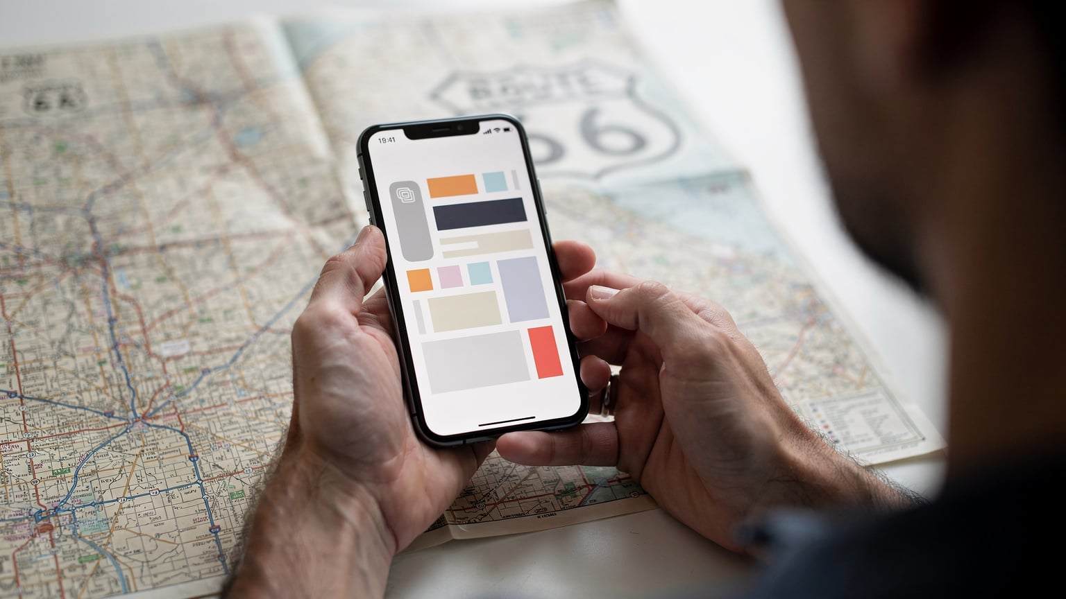 Manos de un viajero sosteniendo un teléfono con la pantalla de activación de una eSIM, con un mapa de la Ruta 66 de fondo.