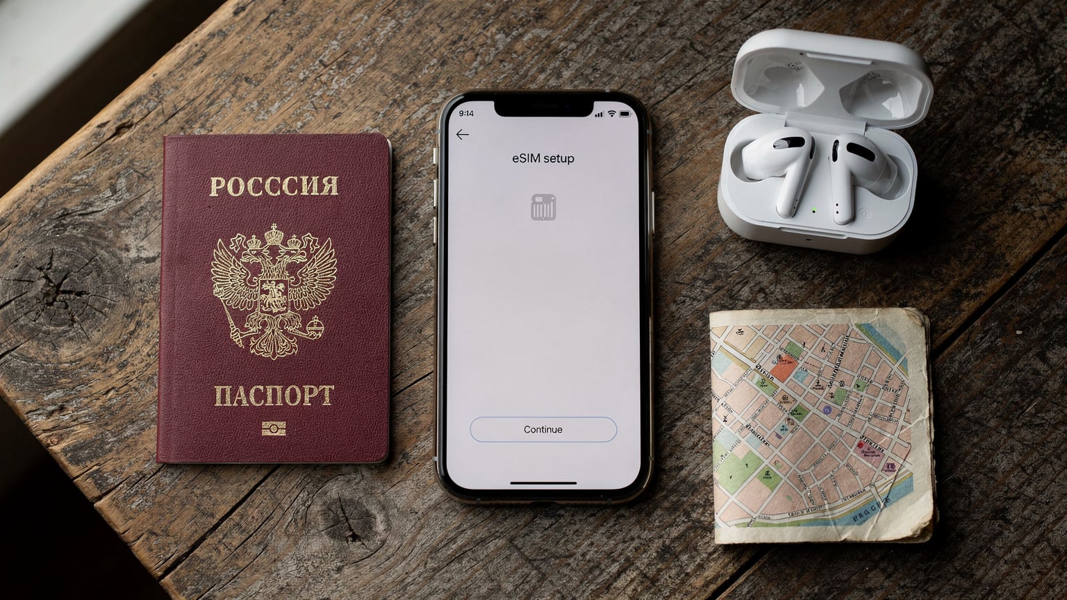 Настольный вид: паспорт, смартфон с открытым приложением eSIM, наушники и небольшая карта города, создающие атмосферу планирования путешествия.