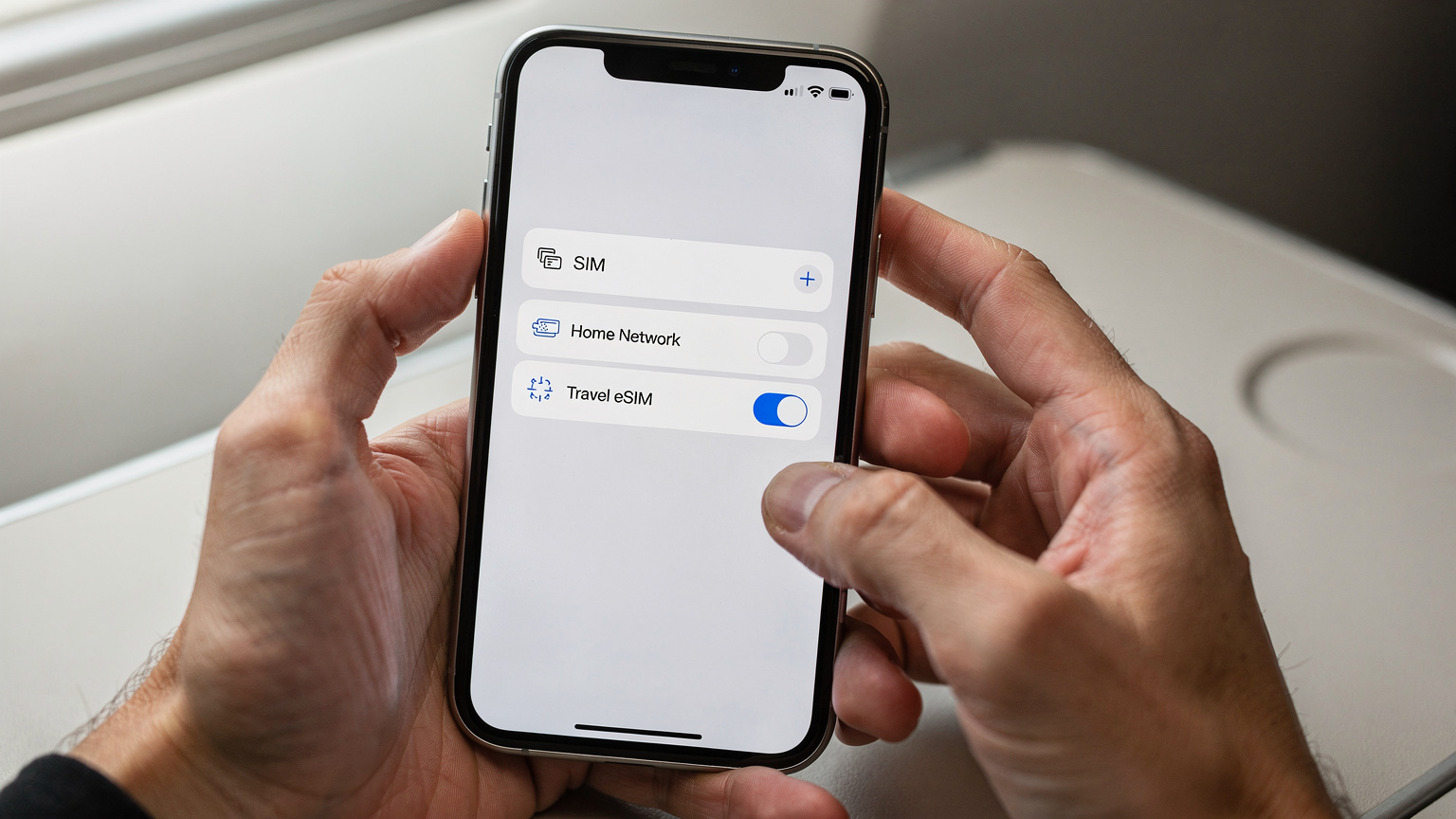 एक व्यक्ति अपने iPhone पर दो अलग-अलग नेटवर्क प्रोफाइल दिखा रहा है, एक भारतीय SIM के लिए और दूसरा eSIM के लिए, जो डुअल-सिम सेटअप को दर्शाता है.