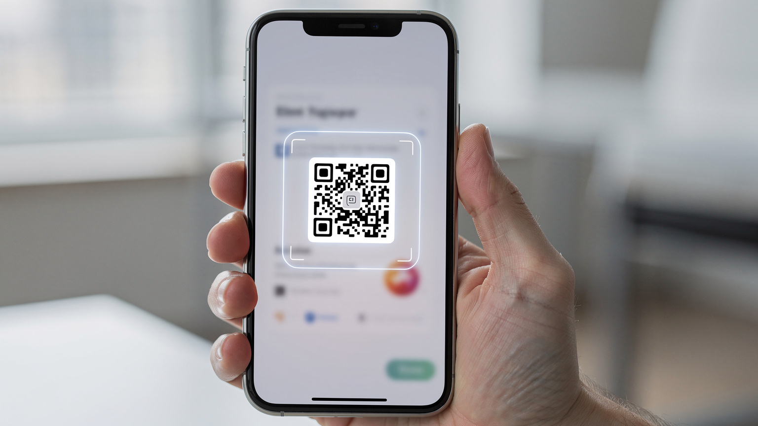 Bir akıllı telefon ekranında, bir QR kod tarama arayüzü gösteriliyor. Ekranda herhangi bir metin veya arayüz detayı görünmeden, sadece tarama alanının görseli ve etrafındaki bulanık arayüz ögeleri ile güvenli bir eSIM aktivasyonu izlenimi veriliyor.