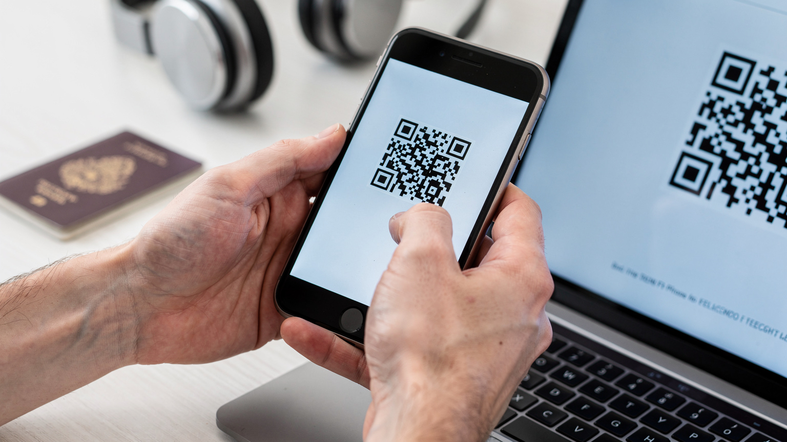 Eine Nahaufnahme von Händen, die ein Smartphone halten, während ein QR-Code auf einem anderen Bildschirm gescannt wird, um eine eSIM zu aktivieren.