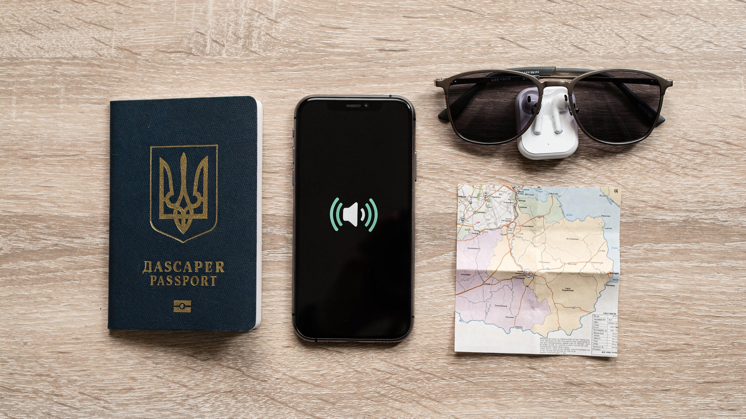 Стилізований плоский макет паспорта, смартфона з активованою eSIM, навушників, сонцезахисних окулярів та місцевої карти Болгарії, розташованих на світлій дерев'яній поверхні.