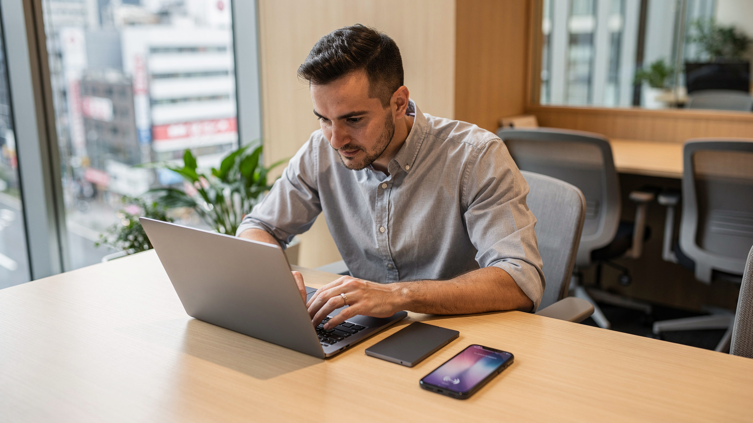 Un nomade digitale lavora sul suo laptop in un moderno coworking space a Shibuya, Tokyo, con il suo smartphone accanto che mostra l'icona dell'eSIM attiva, indicando una connessione affidabile.