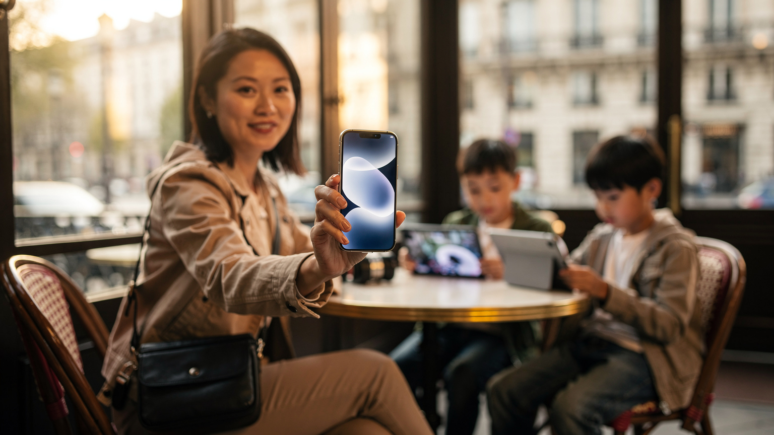 一位母亲在法国巴黎一家时尚的咖啡馆里，用新款iPhone 18（或类似未来的智能手机）向镜头展示eSIM的设置应用界面，她的两个孩子在背景中安静地使用平板电脑，享受着咖啡馆的氛围。