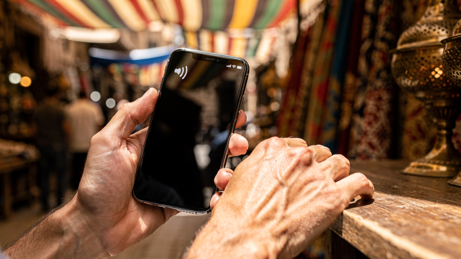 Manos de un viajero sosteniendo un smartphone con una eSIM Cellesim activada, mostrando el icono de la señal de datos activa en el bullicioso Khan el-Khalili, El Cairo.
