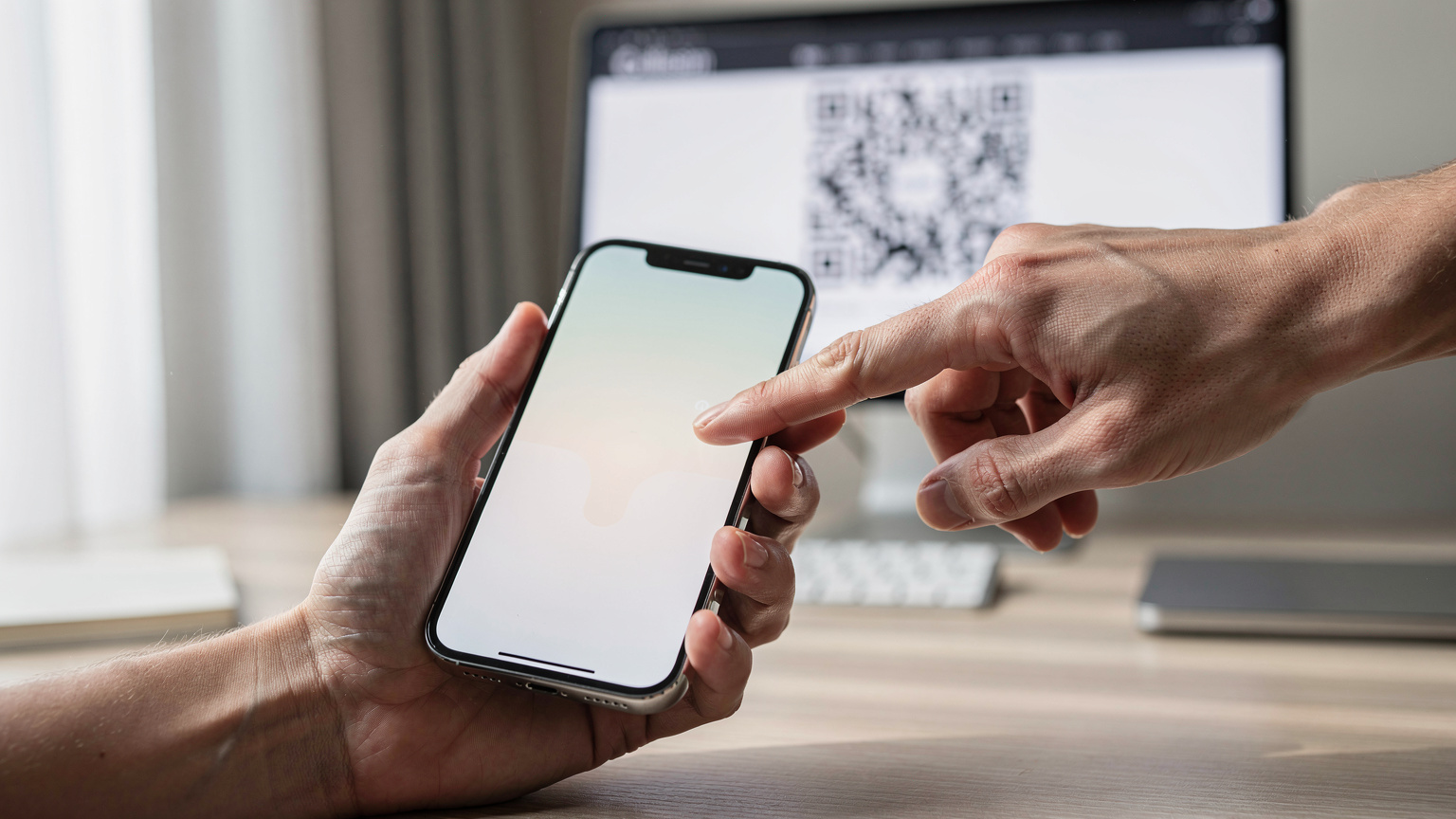 Крупний план рук, що тримають iPhone 17 Pro, на екрані якого відображається процес сканування QR-коду для активації eSIM. На задньому плані, розмито, видно екран комп'ютера з відкритим веб-сайтом Cellesim.