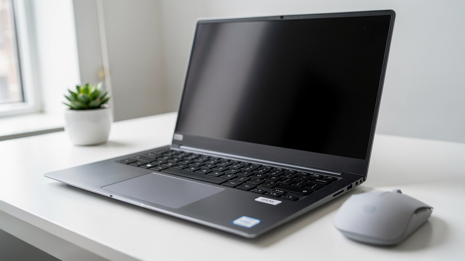 A close-up of a Dell XPS 15 laptop with a subtle eSIM logo sticker, sitting on a desk in a modern office, indicating its cellular connectivity features.