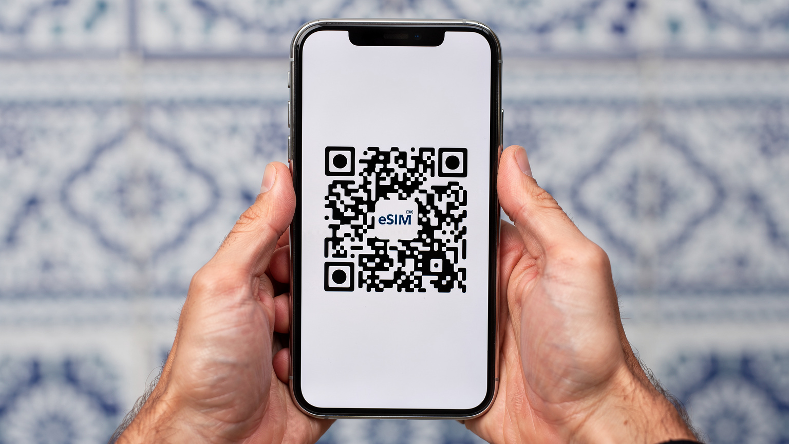 A close-up of a smartphone displaying an eSIM activation QR code, with a traditional Algerian tile pattern in the blurred background, emphasizing ease of digital setup.