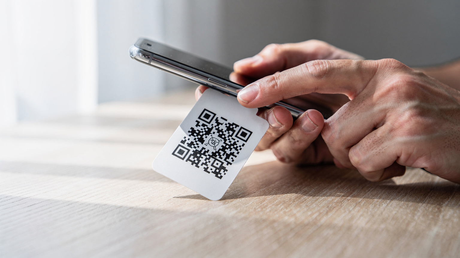 Mână apropiată a unei persoane care scanează un cod QR eSIM cu camera telefonului, într-un mediu minimalist, concentrându-se pe procesul digital de activare.