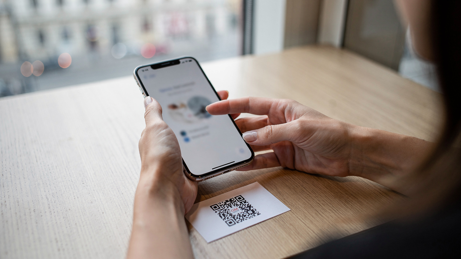 Ruky cestovateľky držia smartfón a skenujú QR kód na papieri, čím aktivuje svoju novú eSIM kartu.