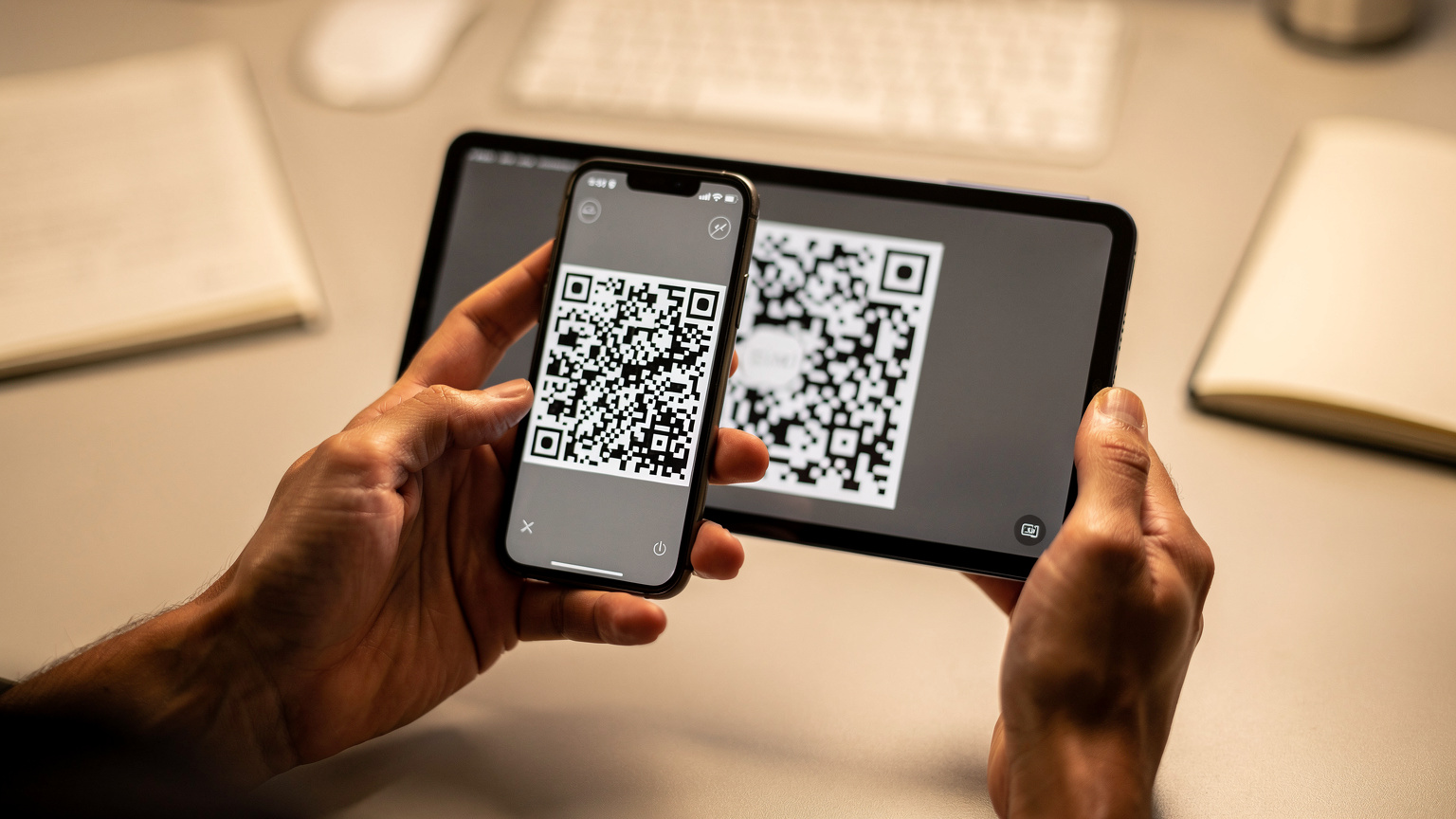 Detailní záběr rukou, které drží smartphone a skenují QR kód pro aktivaci eSIM z jiného zařízení.