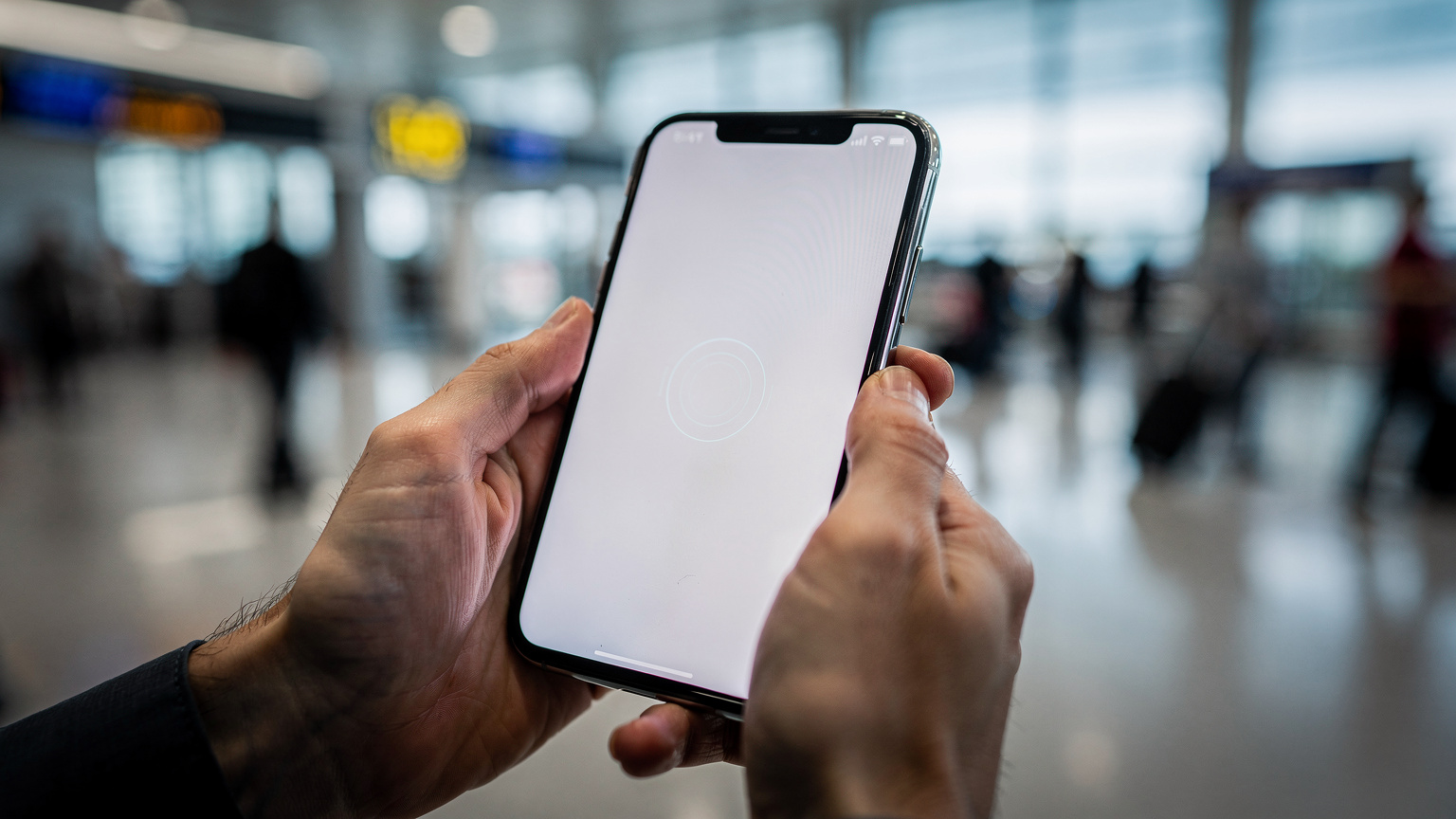 Detailní záběr rukou cestovatele, který drží chytrý telefon a skenuje QR kód eSIM pro aktivaci, s rozmazaným pozadím letištního terminálu, zdůrazňující rychlost a jednoduchost procesu.