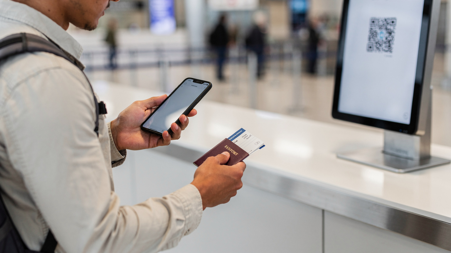 Un viaggiatore sta scansionando un QR code per attivare la sua eSIM al banco del check-in di un aeroporto moderno e ben illuminato, con il suo passaporto e il biglietto aereo in mano.