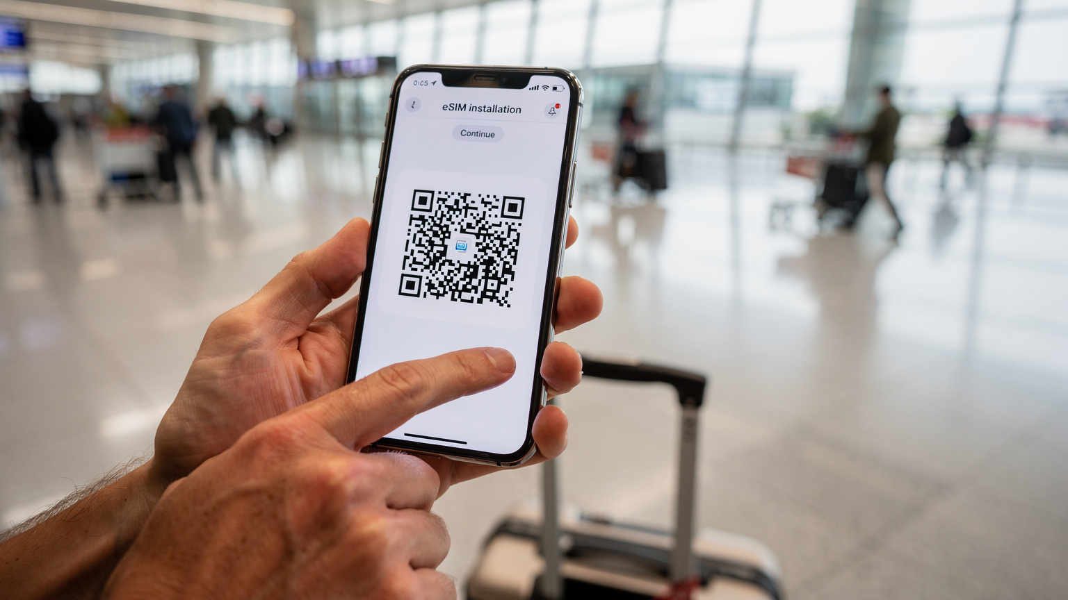 Une personne en train d'installer une eSIM sur son smartphone à l'intérieur d'un terminal de l'aéroport d'Istanbul, juste après l'atterrissage, avec des valises à proximité.