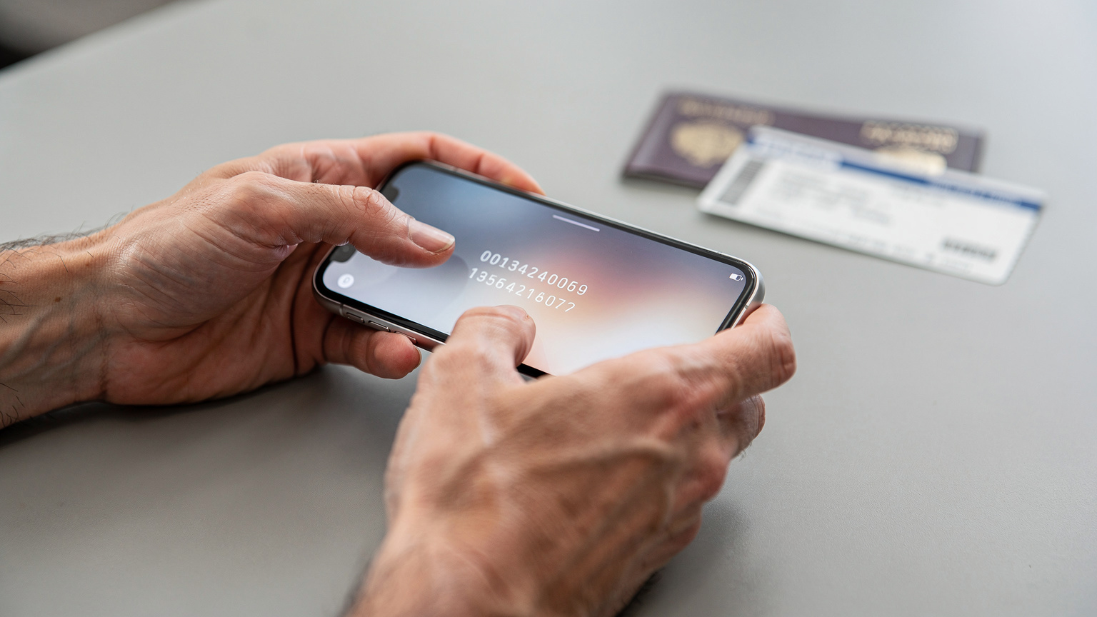 A close-up of hands holding a smartphone, with a virtual keyboard displayed, indicating the manual entry of an eSIM activation code.