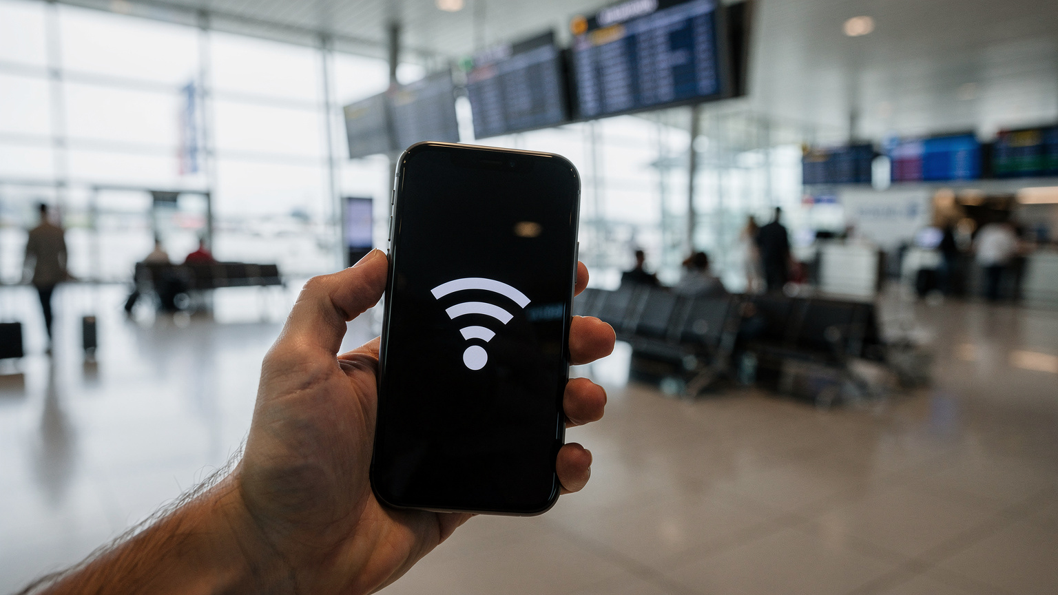 Una mano tiene uno smartphone con un messaggio di errore di connessione WiFi, in un ambiente di aeroporto affollato con schermi di partenza sullo sfondo, creando una sensazione di frustrazione.