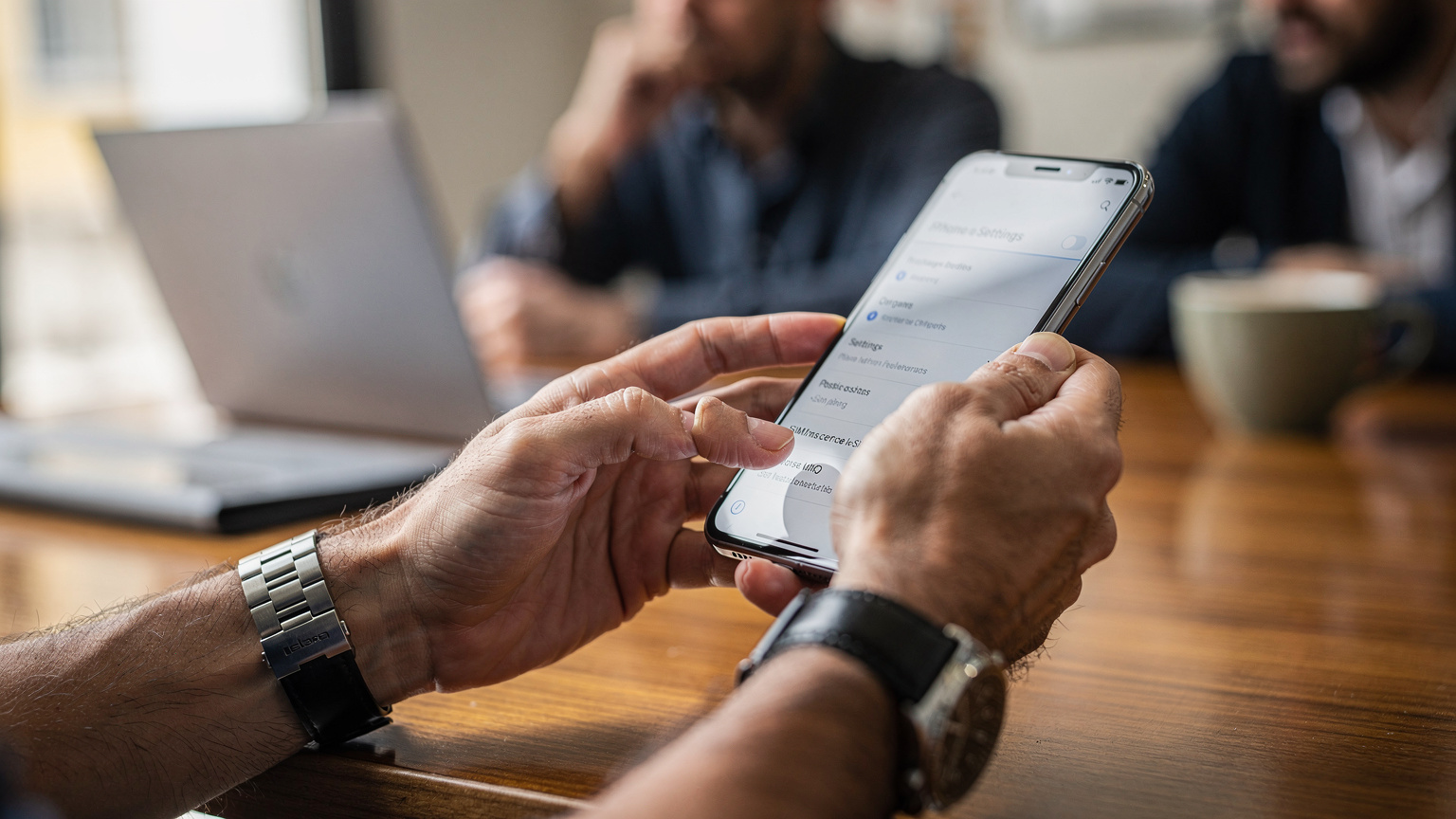 Gros plan sur des mains masculines naviguant dans le menu "Données cellulaires" d'un iPhone, l'écran affichant des options de gestion eSIM avec des icônes de réseau mobile floues en arrière-plan.