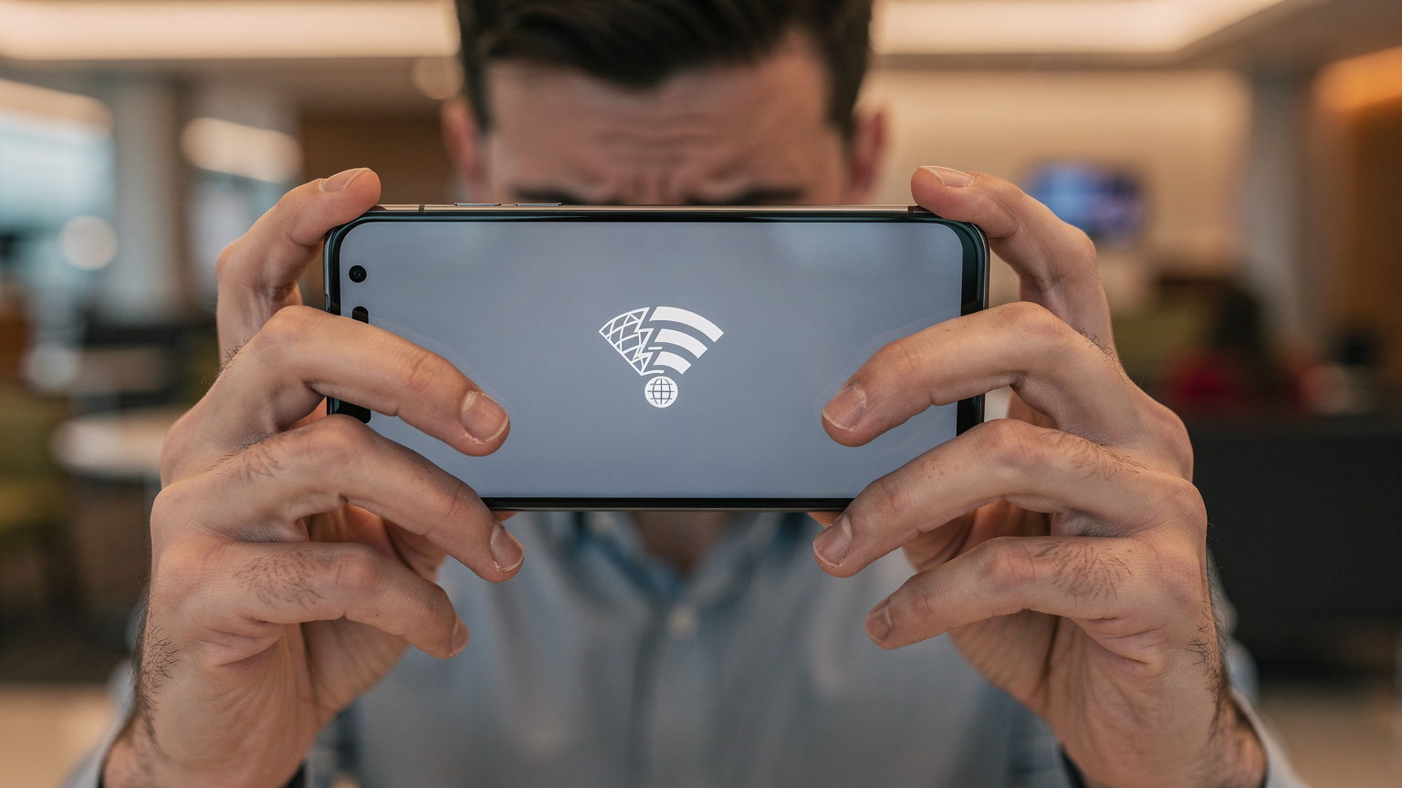 Yurt dışı havalimanında bir bankta oturan, elindeki akıllı telefonunda ağ bağlantısı hatası mesajıyla karşılaşmış, endişeli görünen bir gezginin yakın çekim görüntüsü.