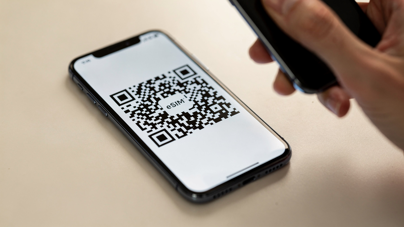 Nærbilde av en mobiltelefon som viser en eSIM QR-kode på skjermen, med en hånd som er i ferd med å skanne den for installasjon.