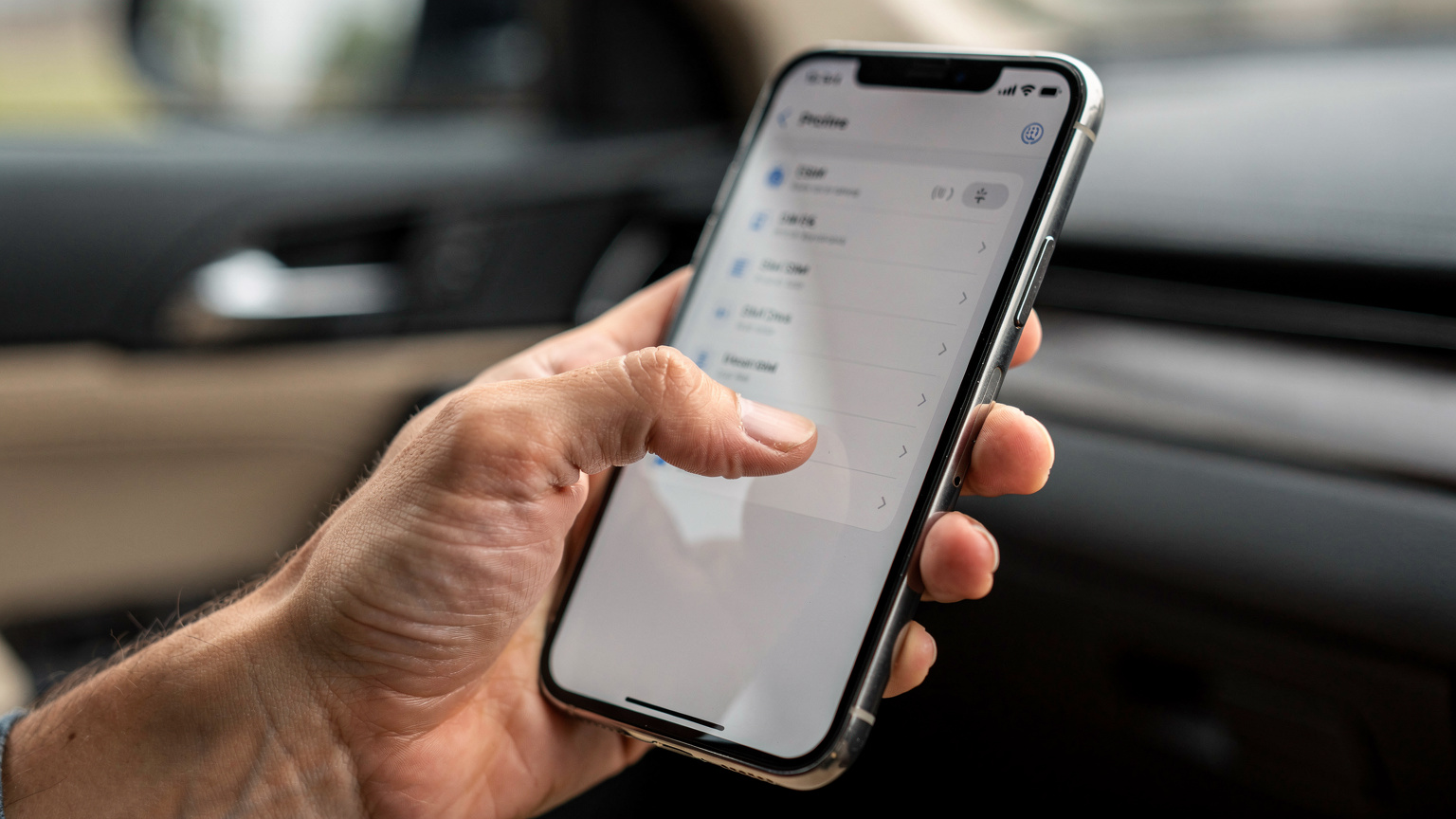 Närbild av en hand som håller en smartphone och sveper genom inställningarna för mobilnätverk, med olika eSIM-profiler listade på skärmen.