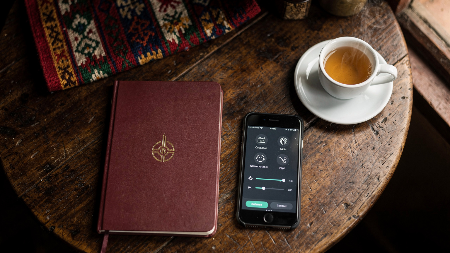 Un primer plano de un pasaporte peruano abierto junto a un smartphone con la pantalla de ajustes de red, sobre una mesa rústica de madera en un café de Cusco, mostrando un ambiente de viaje y tecnología.