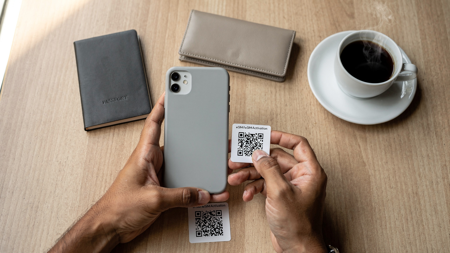 Tangan seorang traveler sedang mengarahkan ponselnya untuk memindai kode QR eSIM di meja kafe yang rapi, dengan paspor dan secangkir kopi di sampingnya.