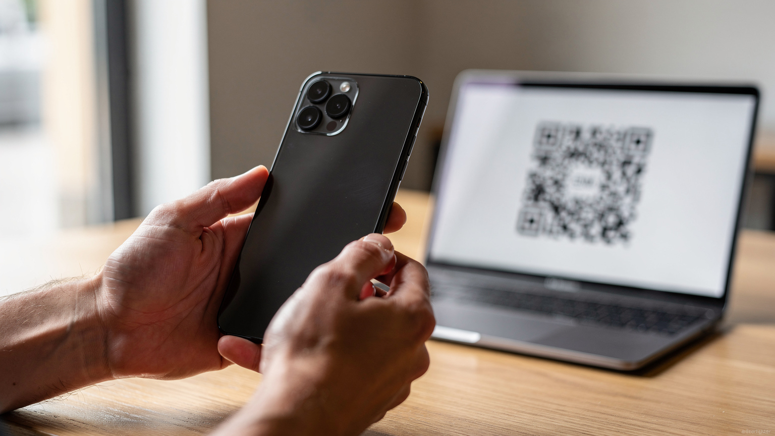 Un primo piano delle mani di una persona che tiene uno smartphone mentre un QR code per l'attivazione di un'eSIM viene scansionato da un altro schermo, in un ambiente luminoso e moderno.