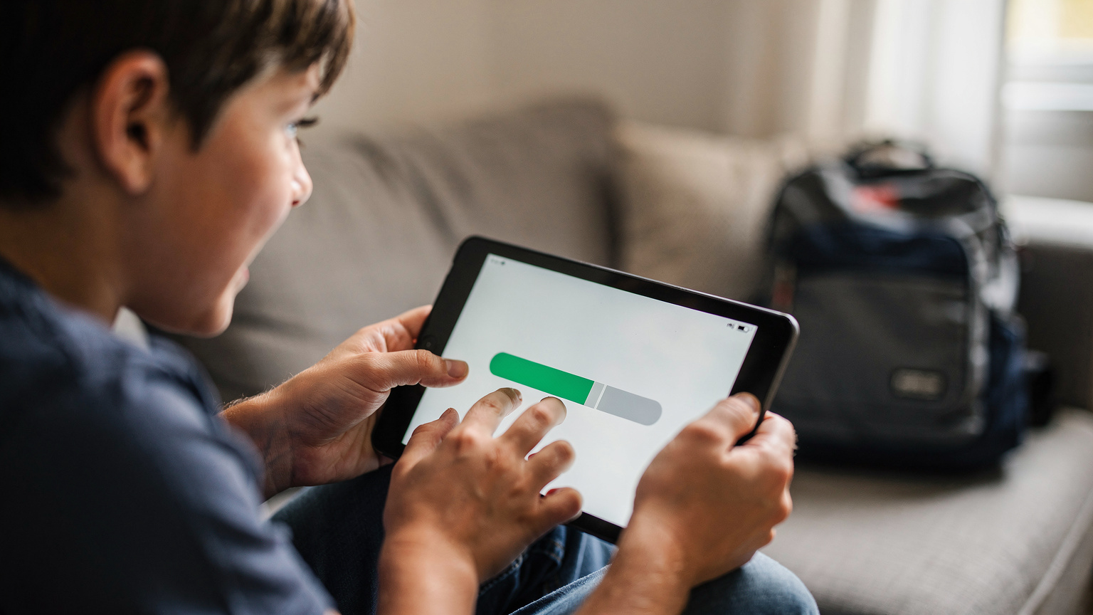 Rodič pomáhá dítěti stahovat oblíbené pohádky na tablet před odletem do Portugalska, aby zajistil zábavu bez nutnosti neustálého připojení k internetu. Klíč k bezstarostné dovolené.