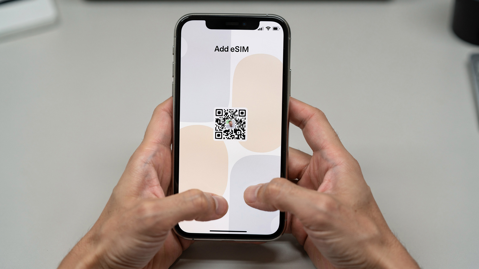 iPhoneのモバイル通信設定画面で、eSIMプロファイルの追加手順を確認しているユーザーの手元。QRコードをスキャンする準備が整っています。