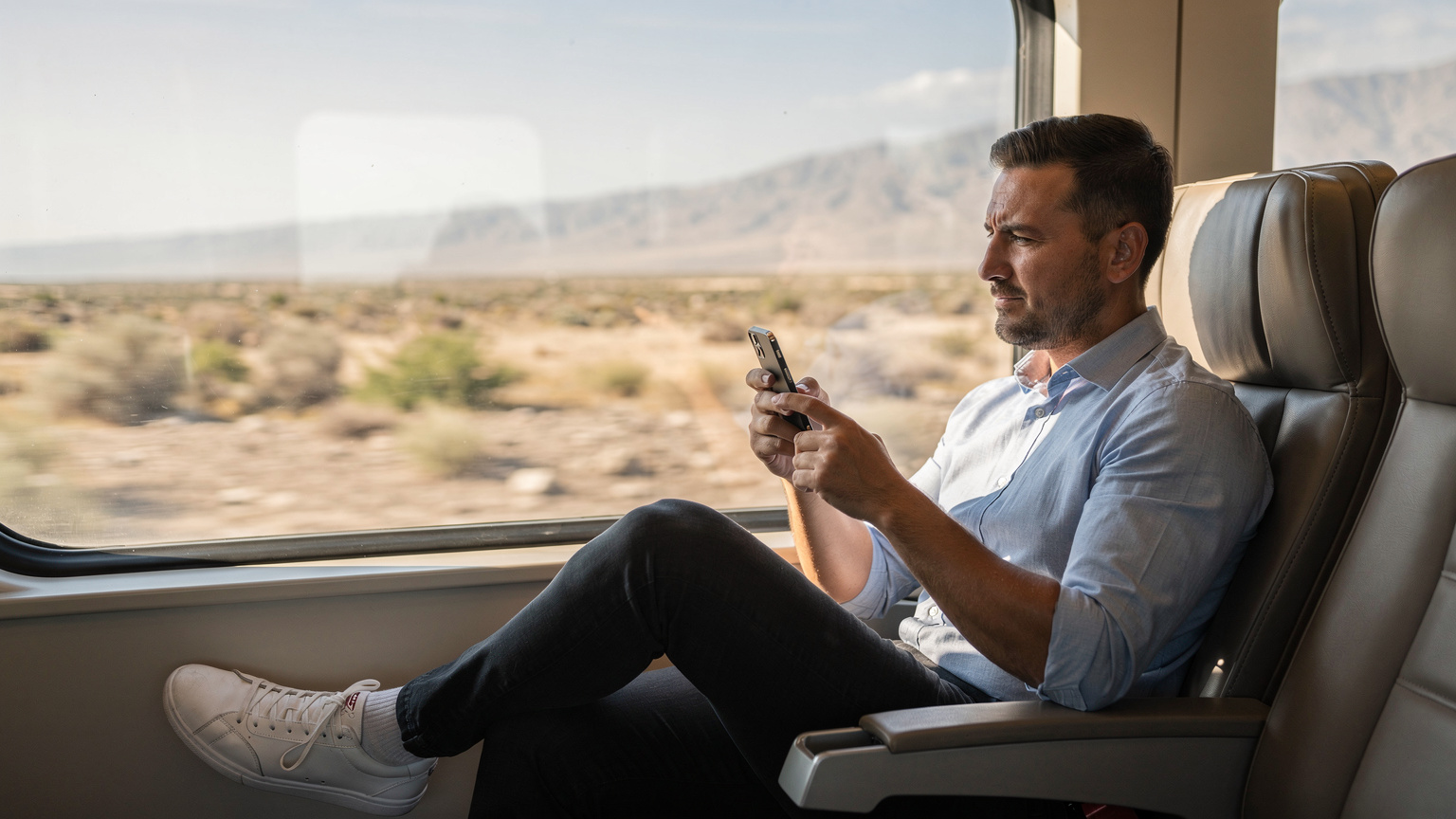 A traveler sits in a modern train carriage in Central Asia, looking out at the passing landscape while casually checking their smartphone, displaying effortless multi-country connectivity.