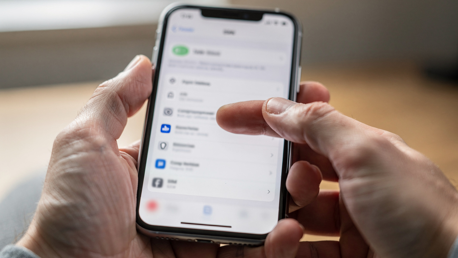 En närbild av en hand som håller en iPhone 11 och navigerar genom inställningsmenyn för mobildata, med fokus på valet av eSIM-profiler.