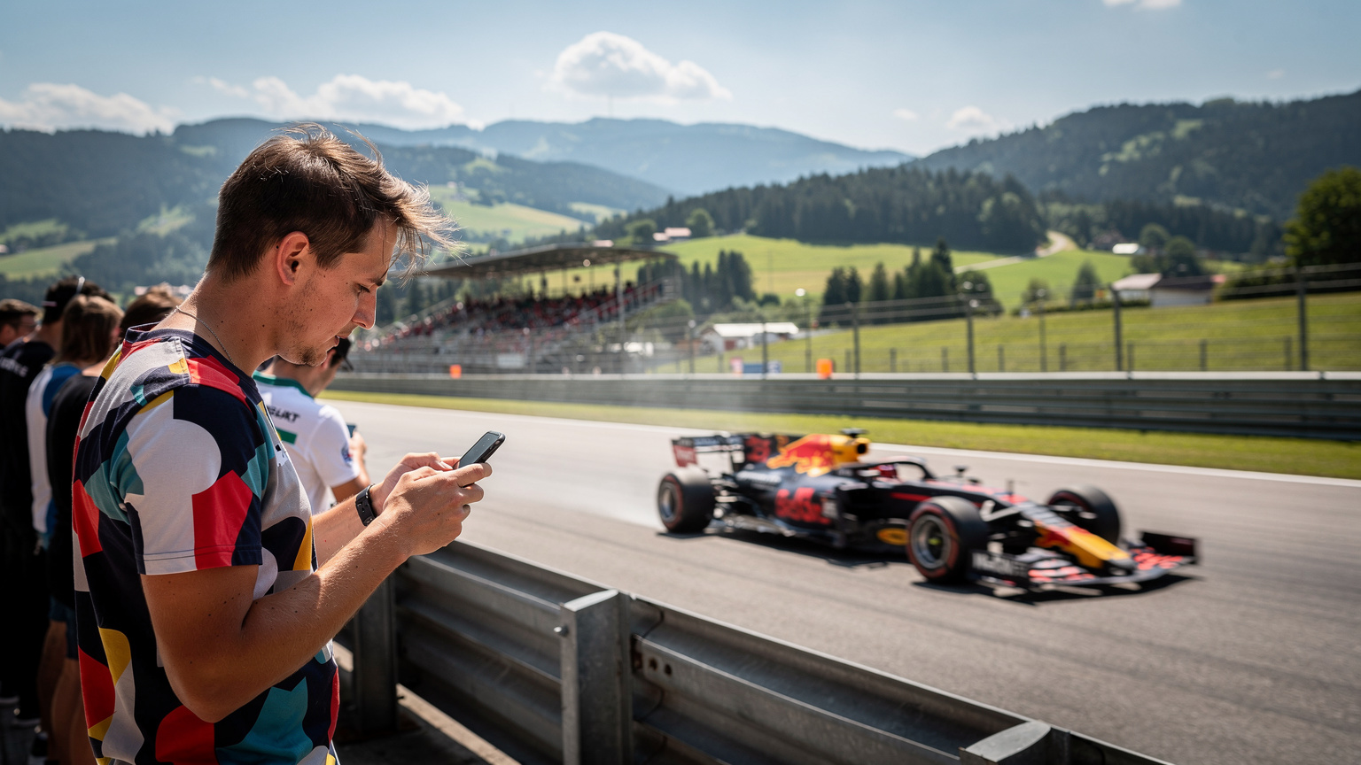Ein Formel-1-Rennwagen rast über eine malerische Rennstrecke, während ein Zuschauer im Vordergrund gebannt auf sein Smartphone schaut.
