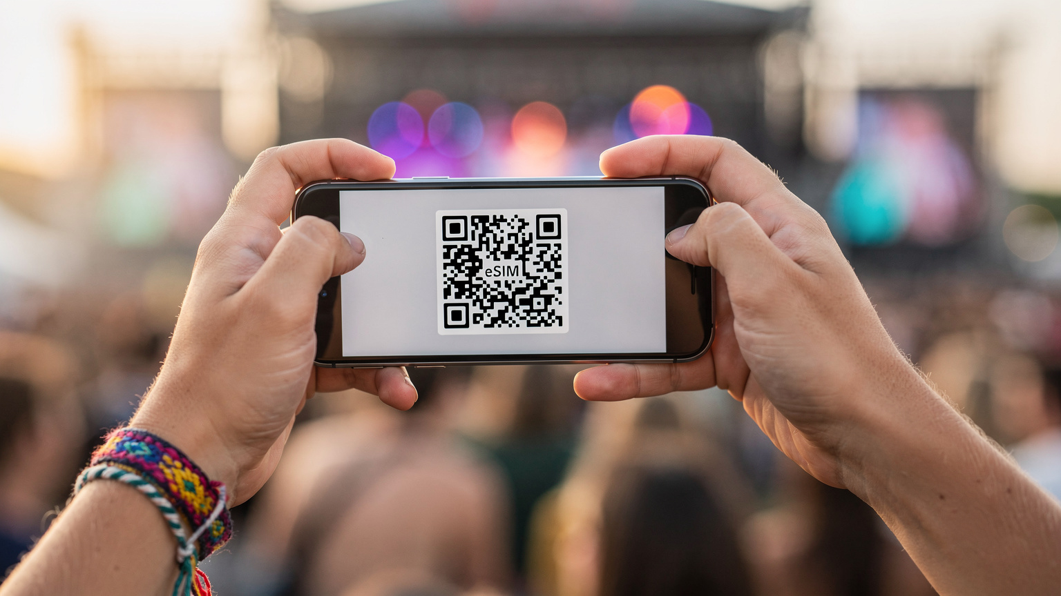 Närbild på en smartphone i en ung persons hand, där en QR-kod för eSIM-aktivering är synlig på skärmen, med en suddig festivalmiljö i bakgrunden.