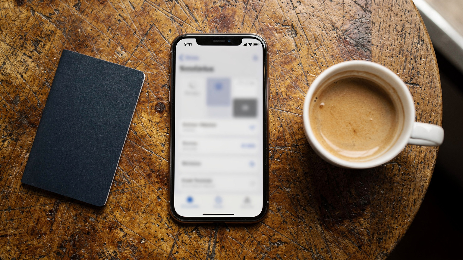Vista cenital de un iPhone mostrando la pantalla de configuración de una eSIM, con un pasaporte y una taza de café en una mesa de madera. Sin texto legible en la pantalla.