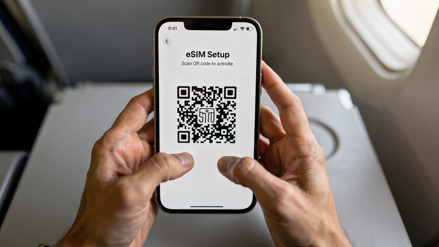 Zbliżenie na dłonie turysty, trzymającego smartfon, na którym widoczny jest ekran aktywacji eSIM z kodem QR, w tle delikatnie rozmazane wnętrze samolotu.