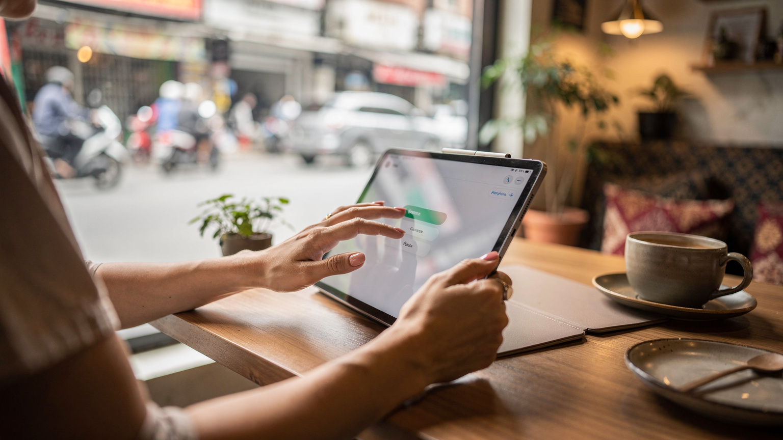 Tangan seorang ibu sedang mengatur pengaturan Screen Time di iPad anaknya, dengan tampilan menu pengaturan seluler yang menunjukkan opsi untuk eSIM, di sebuah kafe bergaya modern di Jakarta, dengan latar belakang jendela yang menampilkan hiruk pikuk jalanan kota.