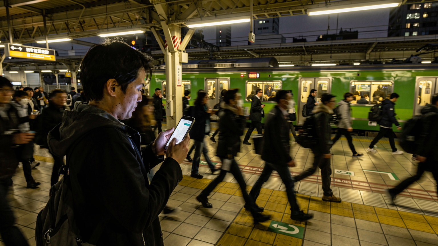 Seorang pelancong menggunakan ponselnya untuk menavigasi stasiun kereta JR Yamanote Line yang ramai di Tokyo.