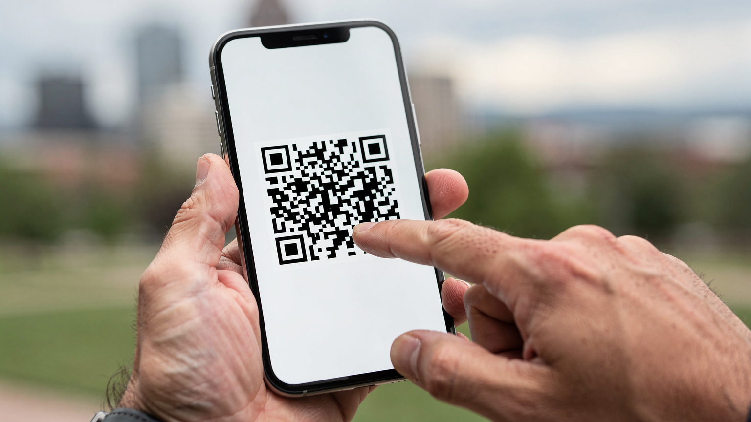 A close-up of hands interacting with a smartphone screen, showing a digital eSIM activation prompt with a QR code, set against a blurred travel background.
