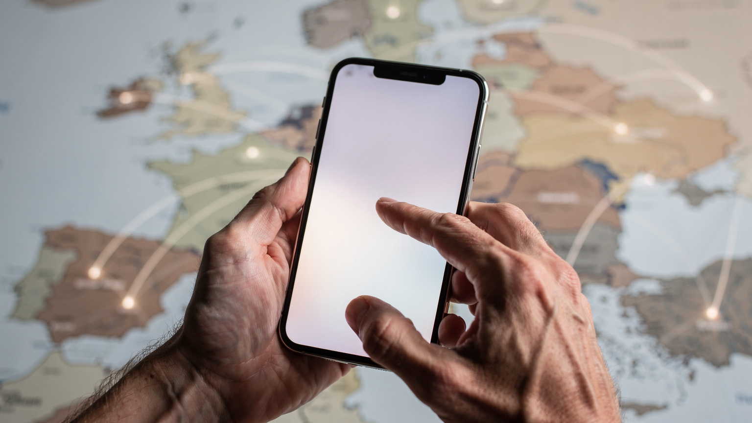 Un primo piano delle mani di una persona che tiene uno smartphone mentre scorre le impostazioni dell'eSIM, con una mappa stilizzata dell'Europa in background che suggerisce il viaggio e la connettività.