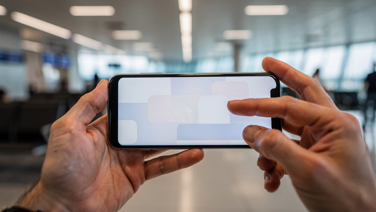 Close-up shot of human hands interacting with a smartphone, tapping an 'Install eSIM' button, with the blurred background of an airport departure lounge.