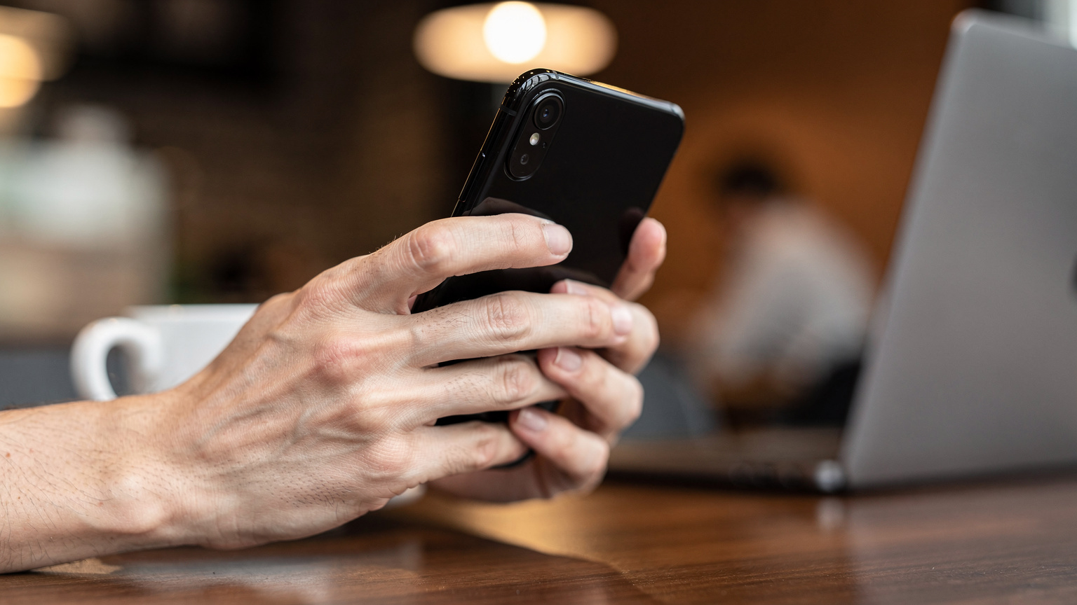 Bir kafede elinde akıllı telefonuyla eSIM aktivasyonu için QR kodu tarayan bir gezginin yakın çekim görüntüsü, ekran parlaklığı ve odaklanmış parmaklarla.