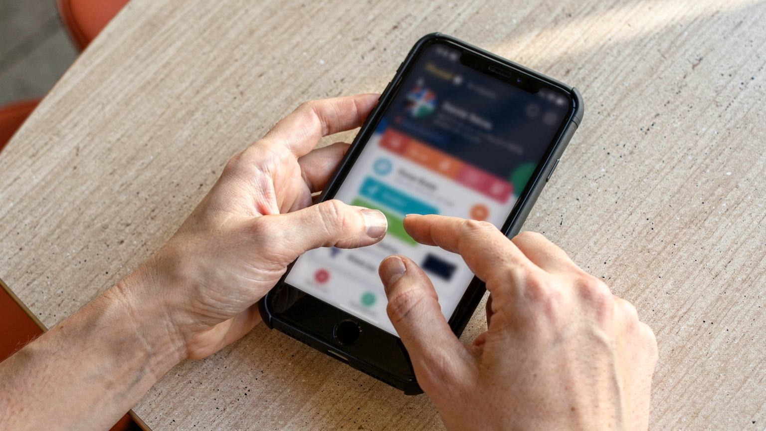 Nahaufnahme der Hände eines Reisenden, der ein Smartphone hält und durch die Cellesim-App scrollt, um verschiedene eSIM-Tarife für eine internationale Reise zu vergleichen.