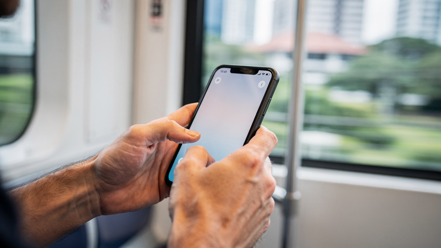 Tangan seorang traveler sedang mengatur pengaturan eSIM di ponselnya saat duduk di dalam kereta MRT Singapura, menunjukkan kemudahan penggunaan.