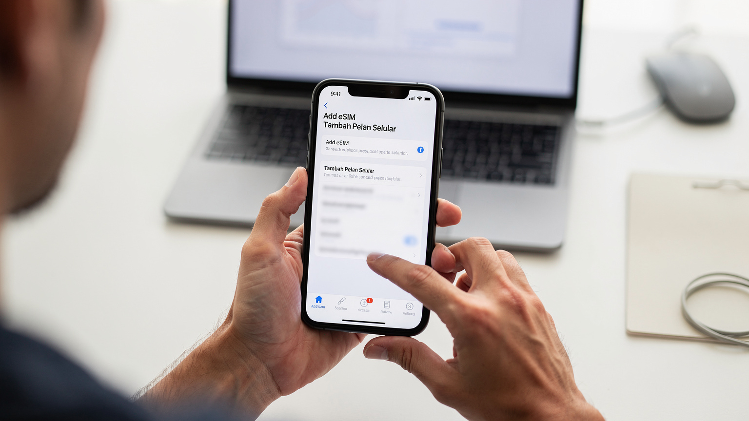 Tangan seorang jurutera telekomunikasi sedang memegang telefon pintar yang memaparkan skrin tetapan rangkaian, dengan jari menunjuk ke pilihan 'Add eSIM' atau 'Tambah Pelan Selular'.
