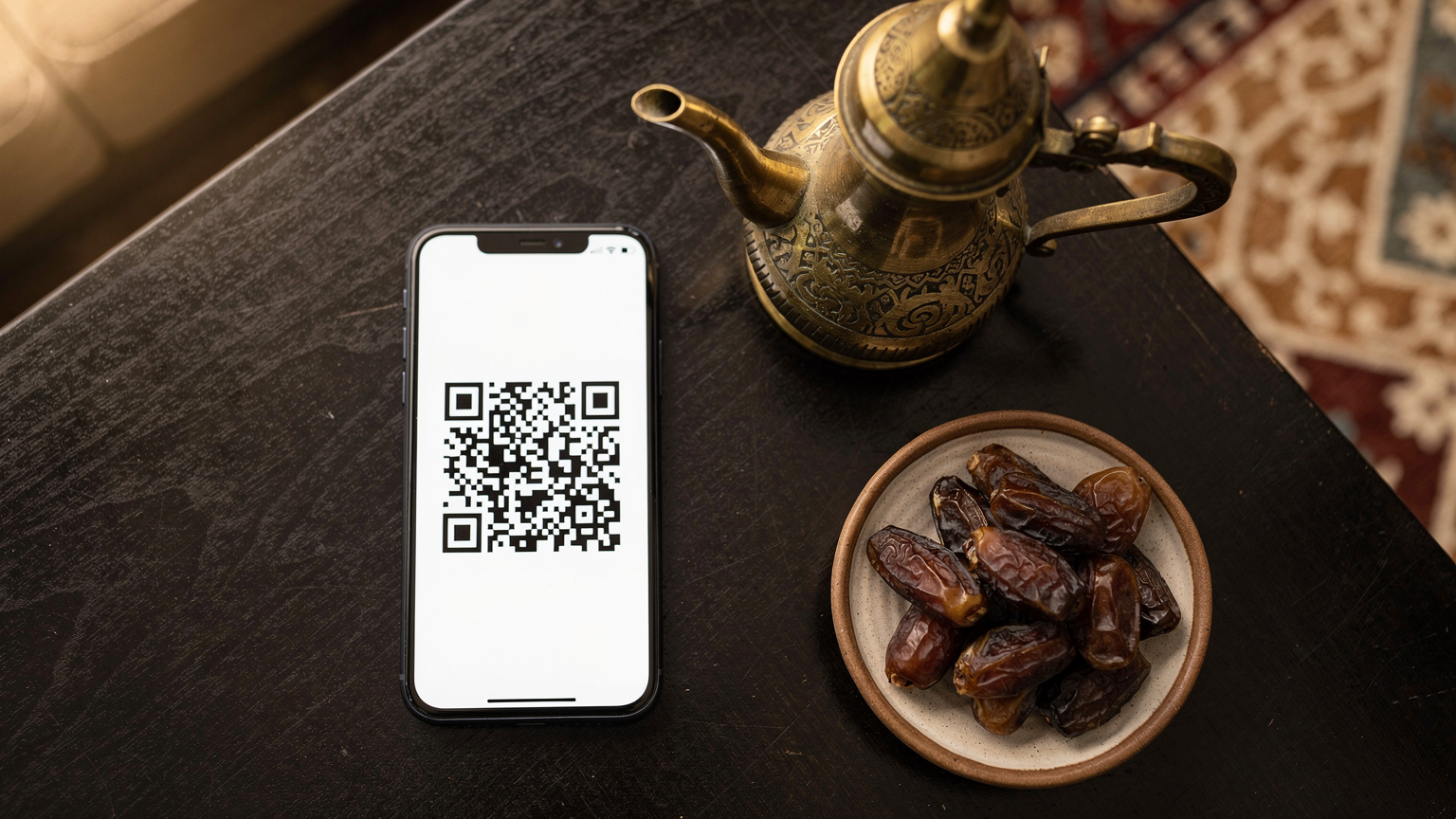 A smartphone screen clearly displays an eSIM QR code, set on a dark wooden table beside a traditional Arabic coffee pot (dallah) and a plate of dates, evoking a calm, culturally rich setting for eSIM activation.