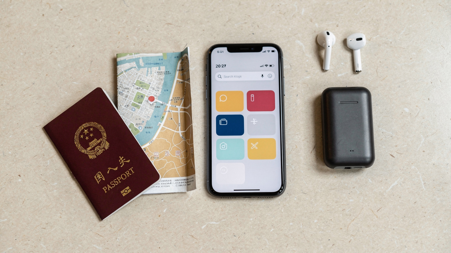 俯視角度拍攝的旅行必備品,包括護照、智能手機(顯示 Cellesim 應用界面)、耳機、便攜充電寶和一張香港地圖,擺放在一張簡潔的咖啡桌上。