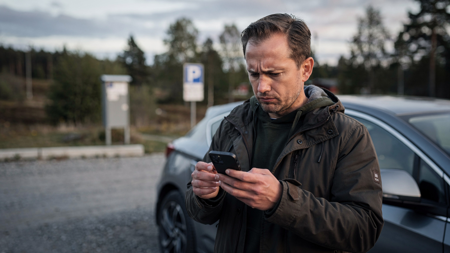 En resenär med en orolig min på en rastplats, tittar på sin smartphone-skärm som visar ett anslutningsfel eller svag signal.