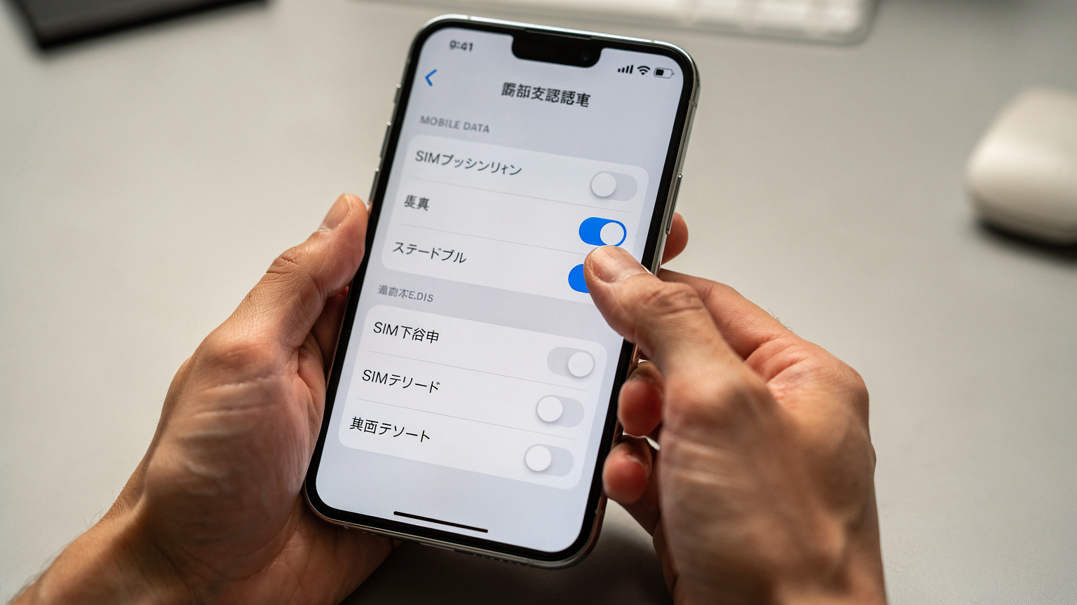 最新のスマートフォンで複数のeSIMプロファイルを管理し、データローミング設定を慎重に確認している日本人の手元。