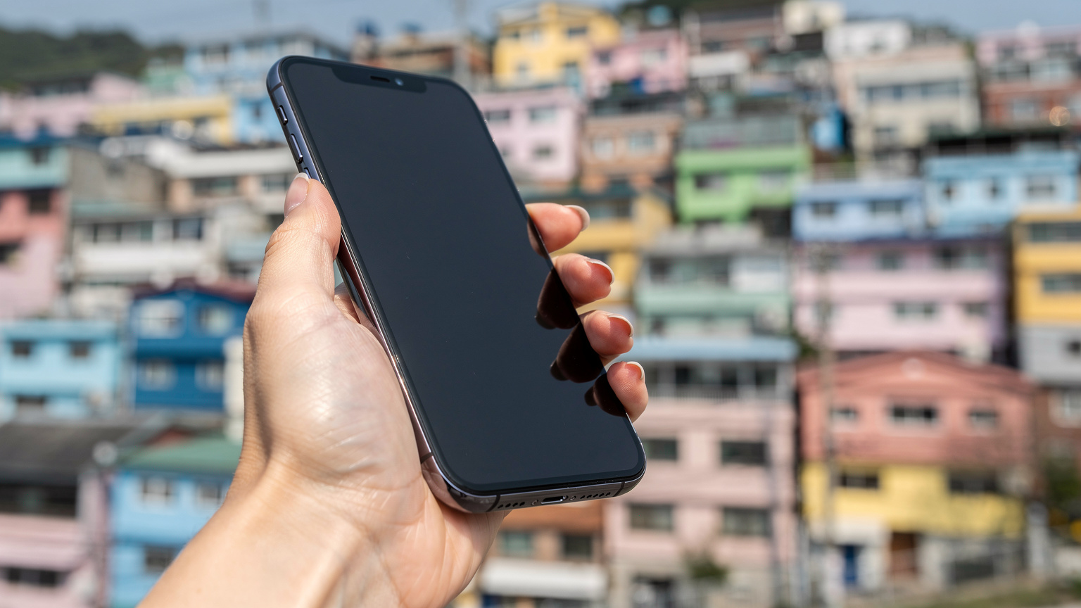 韓国・釜山の甘川洞文化村で、スマートフォンでeSIMのキャリア設定を切り替えている旅行者の手元。