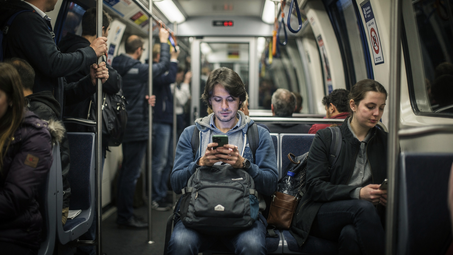 Londra'nın yoğun metro istasyonlarından birinde, elindeki telefonuna dalmış bir yolcu, çantasını arkasında bırakmış durumda.